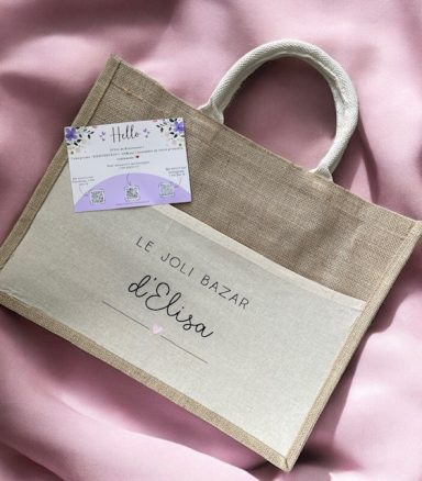 Sac en toile beige avec inscription "Le joli bazar d'Elsa" et étiquette décorative.