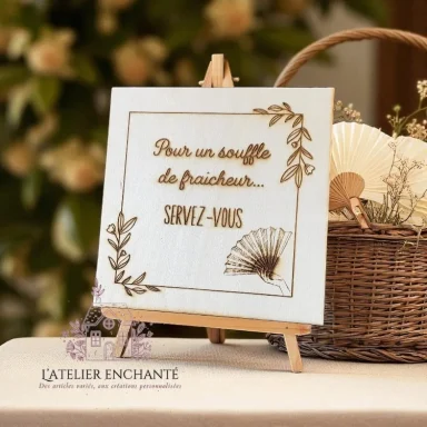 Panneau en bois avec inscription artistique, décoré de feuilles et ventilateur.